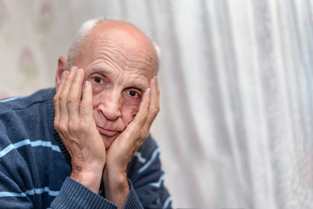 一个垂头丧气的秃头退休老人双手抱头坐在医院的病床上图片下载