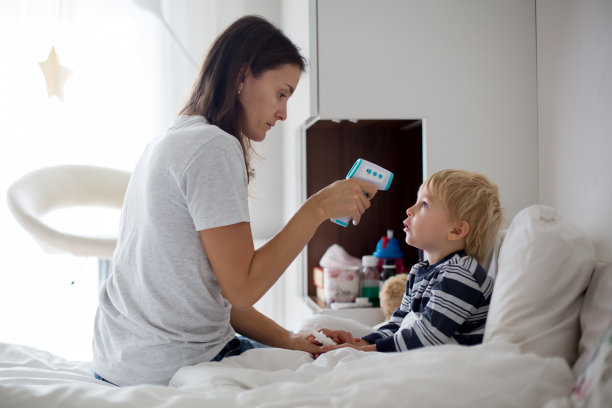 母亲正在用数字体温计检查儿子是否发烧图片下载