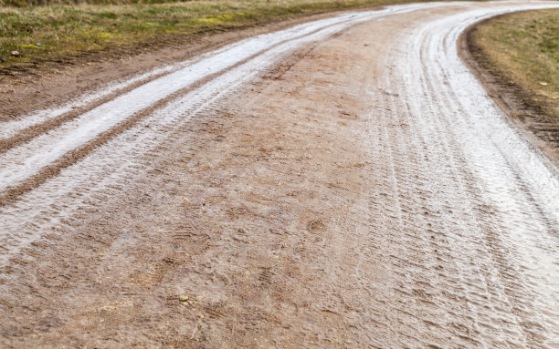 潮湿的转弯乡村道路，有轮胎印图片下载