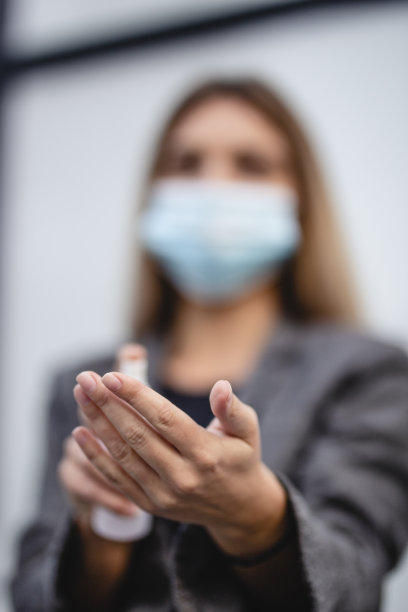 年轻女商人戴口罩用洗手液特写图片下载