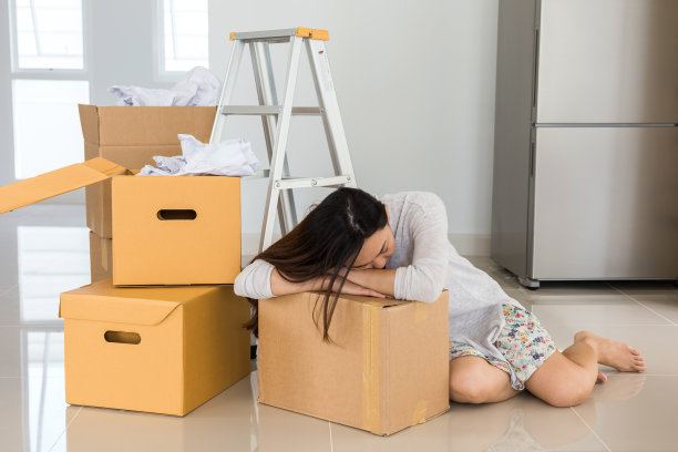 疲惫的女人在新家，睡在移动的箱子上图片下载