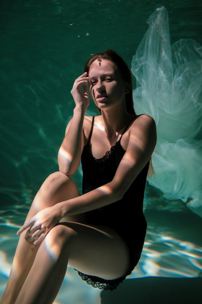 水下穿着黑衣的美丽女孩。水魔法。水下摄影。艺术图片下载