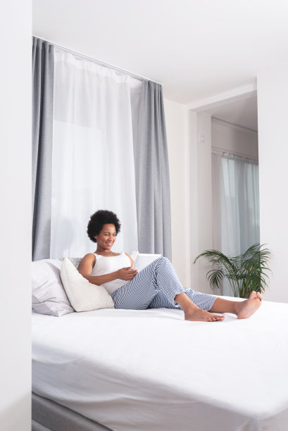 快乐的女人在床上用电子平板电脑在家图片下载