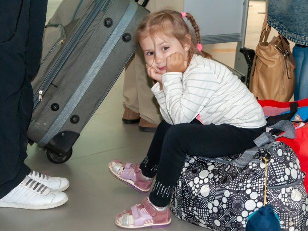 一个四岁的小女孩坐在机场的行李上图片下载