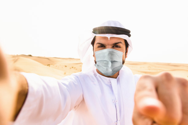 在沙漠中戴着口罩自拍的阿拉伯男子图片下载