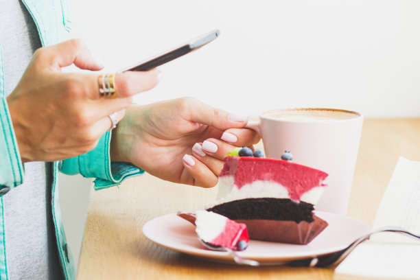 一个女人拍了张照片，盘子里有一杯卡布奇诺和一块甜点图片下载