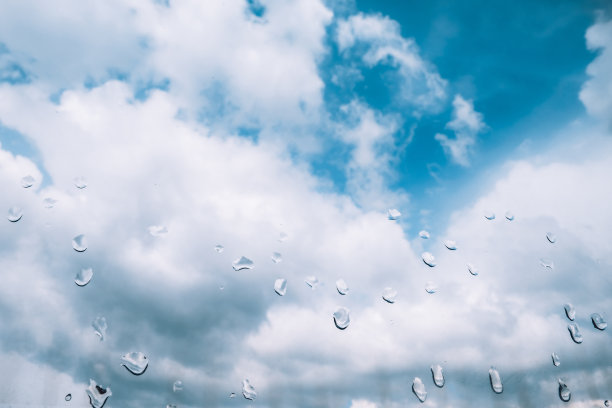 在雨天，蓝天和蓬松的白云透过湿漉漉的窗户图片下载