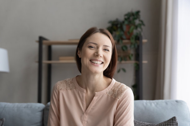 微笑的年轻女子坐在沙发上的大头照图片下载