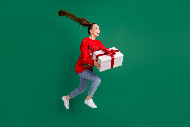 全身的档案照片疯狂的漂亮女士跳高rush圣诞派对家庭抱大的礼盒现在兴奋的满足父母穿红色丑陋的毛衣牛仔裤鞋子孤立的绿色背景图片下载