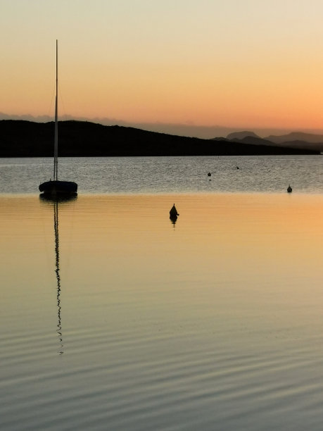 落日的背景是海面上的小岛和小船。图片下载