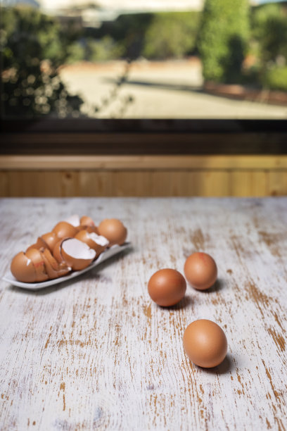 早上，鸡蛋和蛋壳放在窗户旁边的白色桌子上图片下载