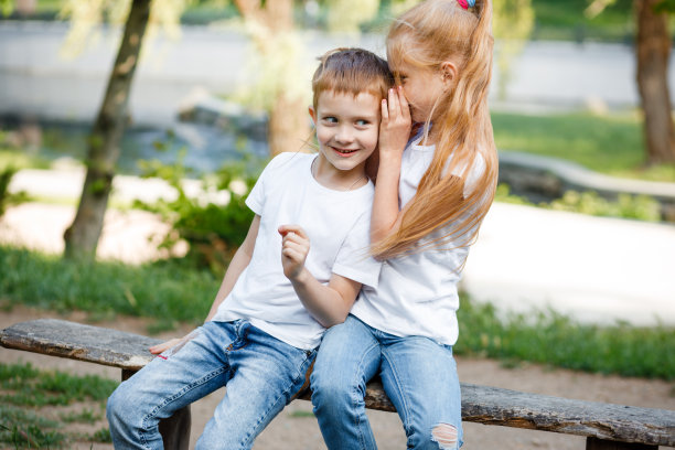那女孩在耳边低声说了一个秘密。孩子们去公园散步。图片下载