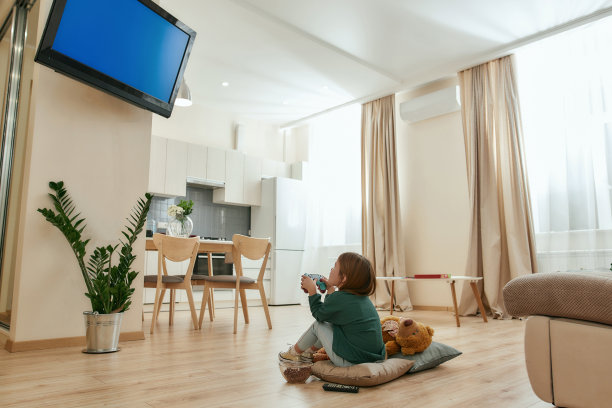 一个可爱的小女孩抱着手柄在电视上玩电子游戏，而坐在地板上盘腿图片下载