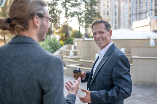 两个男性商业伙伴在商务中心外面喝咖啡休息图片下载