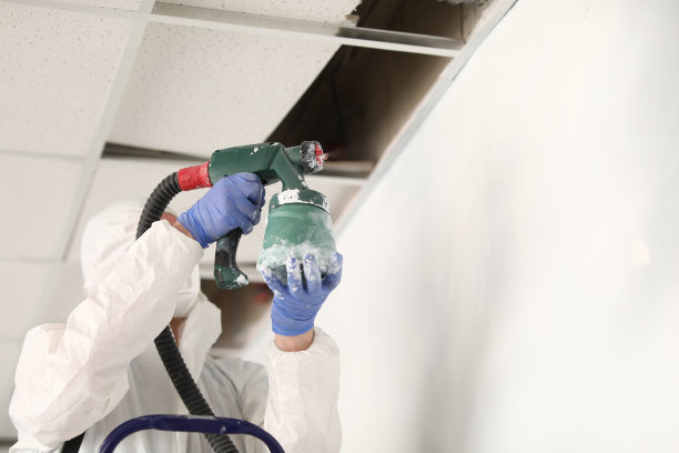 油漆工手持绿色喷枪，将天花板下的墙漆成白色。图片下载