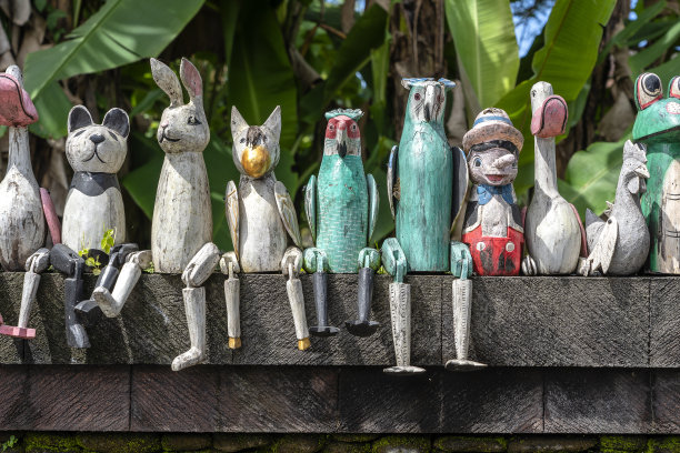 印度尼西亚巴厘岛乌布玩偶店附近的石头篱笆上，旧的木制纪念品。特写镜头图片下载