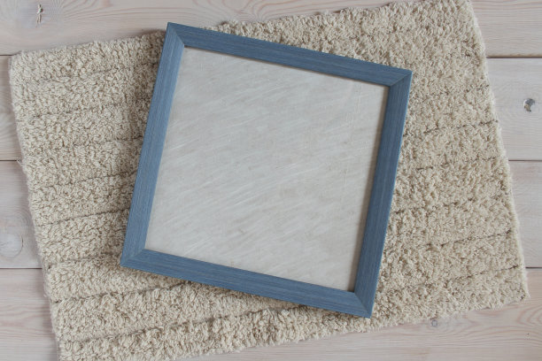 蓝色相框放在毛茸茸的白色地毯上。轻木表面上的物体。图片下载