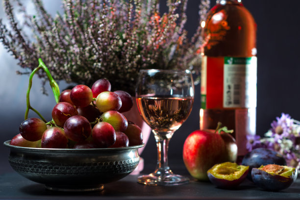 成熟的葡萄，一杯葡萄酒，一个苹果，李子和花图片下载