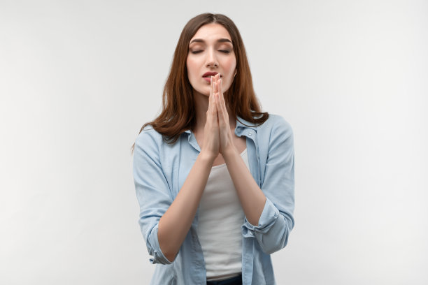 美丽女孩的肖像保持她的眼睛闭着祈祷。工作室拍摄，白色背景图片下载