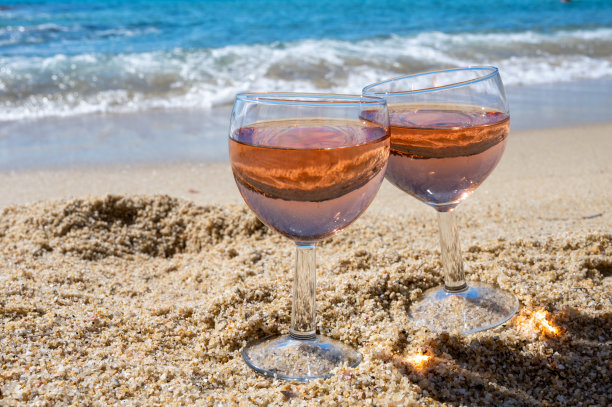 两杯当地的玫瑰葡萄酒在白色的沙滩和蓝色的地中海背景，靠近勒Lavandou，法国普罗旺斯图片下载