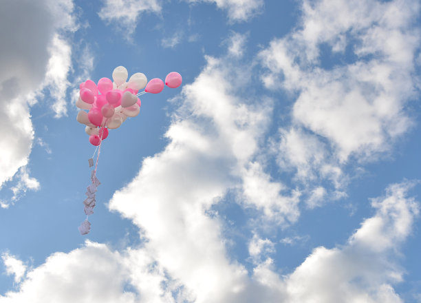 白色和粉色的婚礼气球上写着祝福，在蓝天白云的映衬下飞翔。放置你的文本。Copyspace。图片下载