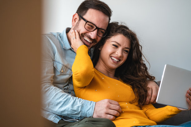 微笑的情侣拥抱在一起看平板电脑库存照片图片下载