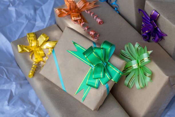 许多礼品盒用漂亮的蝴蝶结绑在灰色的帆布上。图片下载