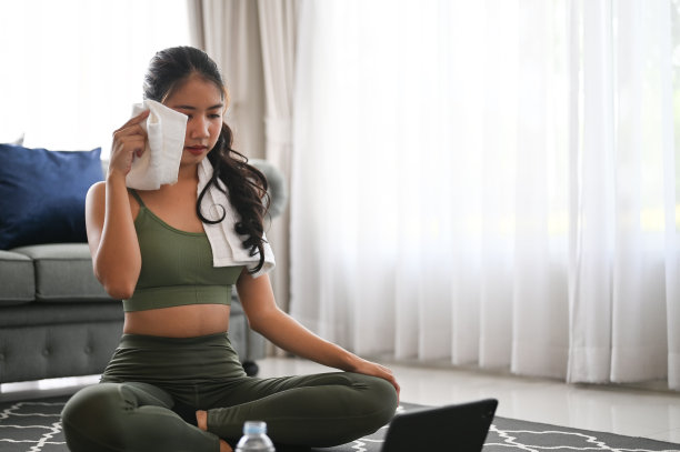 迷人的健身女士在家里用毛巾擦拭汗水。图片下载