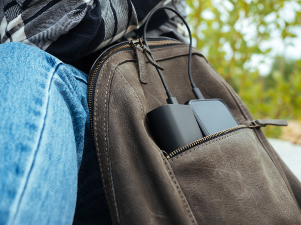 手机是用电源充电的。在日常生活中使用现代科技。电话和电源在游客的皮包里。方便的现代小玩意，舒适的生活图片下载