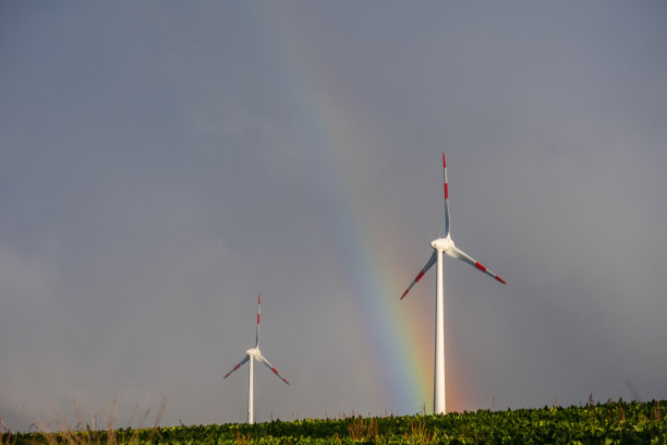 巨大的彩虹在风力涡轮机所在的土地上图片下载