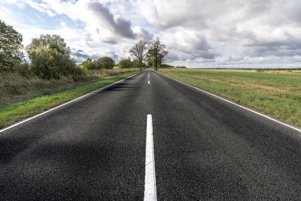 柏油路用白色的分隔带在蓝天下的田野里图片下载