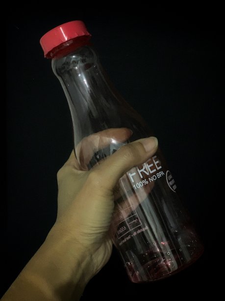 手持黑色背景的瓶子图片下载