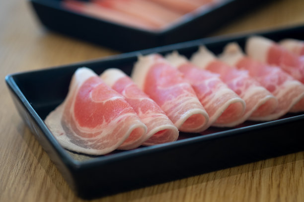 薄的新鲜五花肉放在黑色的盘子里，可以用来做涮锅、寿喜烧或日本火锅。图片下载