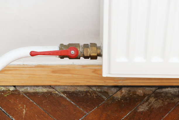 公寓里的白色散热器。散热器。白色暖气片，带有水龙头，可关闭向暖气片供应的水。图片下载