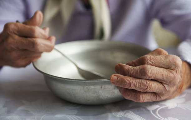 从以上观点。一个90岁的老祖母手里拿着一个空铝碗和勺子，贫穷和贫穷，老一辈人的饥饿。图片下载