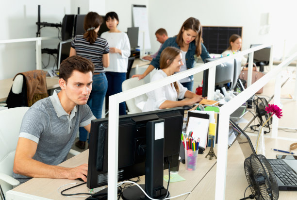 英俊的年轻人自信地在现代开放式办公室电脑上工作图片下载