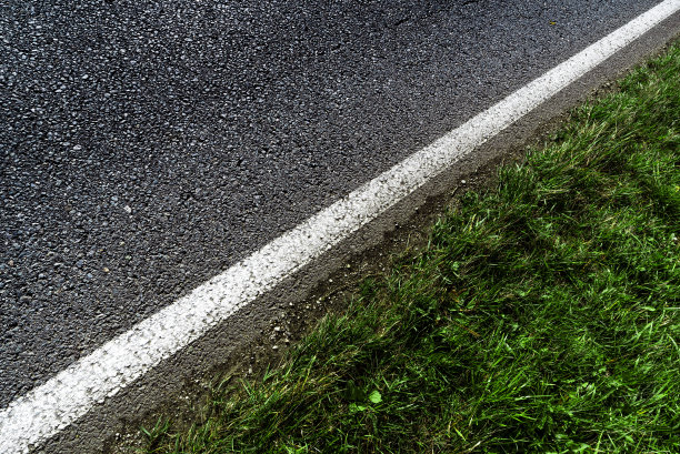 柏油路的对角线照片，白色的边框带绿色的草的观点图片下载