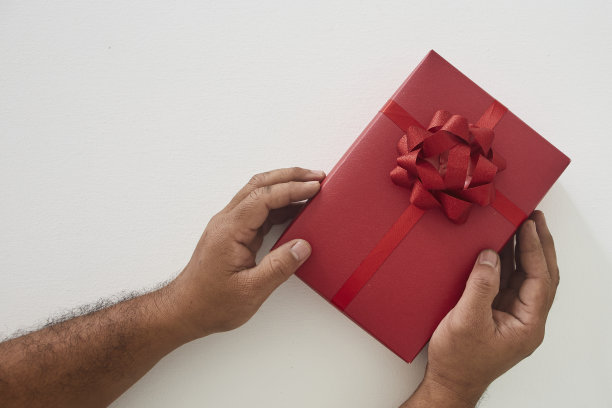 男人手里拿着一个白色的红色礼品盒图片下载