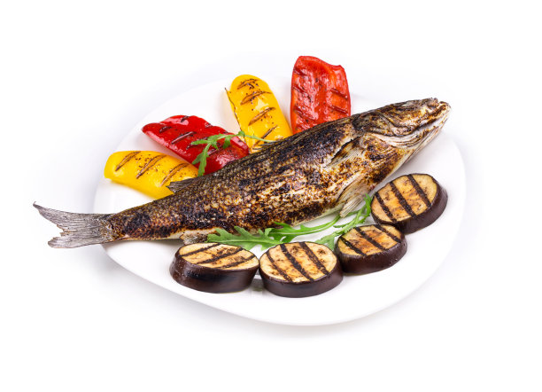 烤鲈鱼和蔬菜在盘子里。图片下载