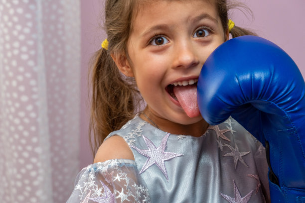 小女孩戴着蓝色拳击手套，穿着缀满星星的节日礼服图片下载