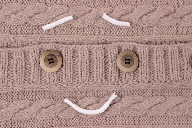 针织米色毛衣与木制扣子关闭。温暖的女夹克与美丽的针织图案宏。羊毛轻开襟女衫。漂亮的针织纹理背景与漂亮的图案。俯视图图片下载