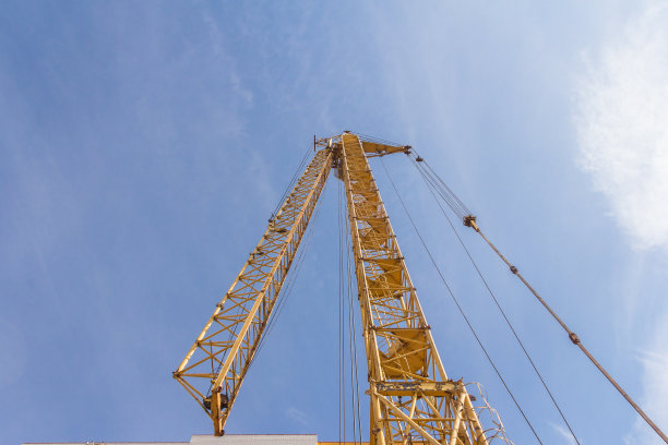 建筑工地的塔吊。在天空背景下降下塔吊图片下载