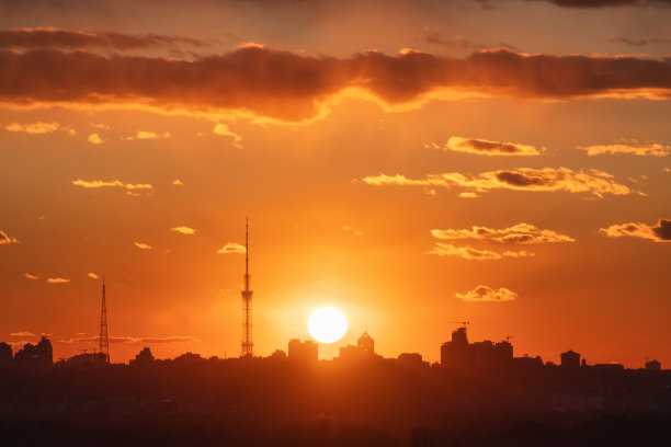 美丽日落下的基辅城市剪影。鸟瞰图的建筑物对抗彩色的橙色天空与太阳和红色的云。城市景观。市中心的背景。城市的天际线。城市景观图片下载