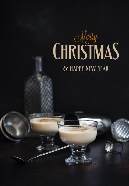 蛋奶酒是传统的圣诞酒精饮料，两杯，肉桂和肉豆蔻在黑暗的桌子上，酒吧工具，圣诞装饰和文字-圣诞快乐和新年快乐图片下载
