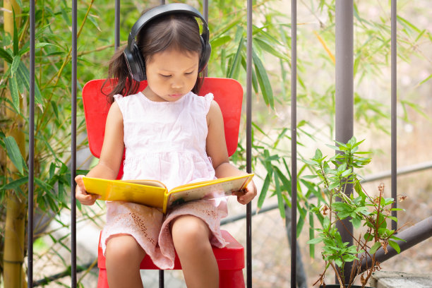 一个女孩在她的家外面看书。远程学习。素材图片