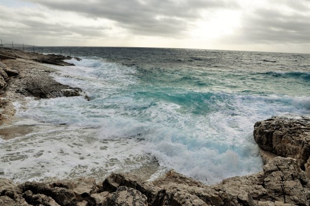 以地平线为背景，海浪撞击岩石。图片下载