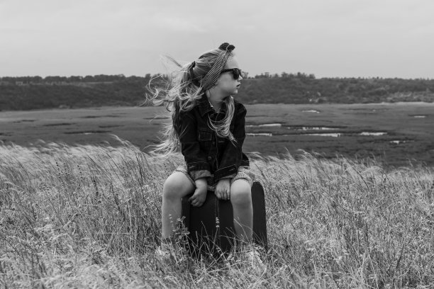 金发碧眼的小女孩穿着牛仔夹克，黑色太阳镜，蓝色的裙子和复古的手提箱在野外，时尚的孩子图片下载