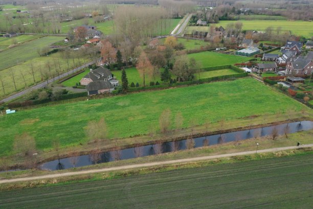 鸟瞰图，在一个小村庄的边缘，几乎是空旷的草地在不同的绿色阴影中图片下载