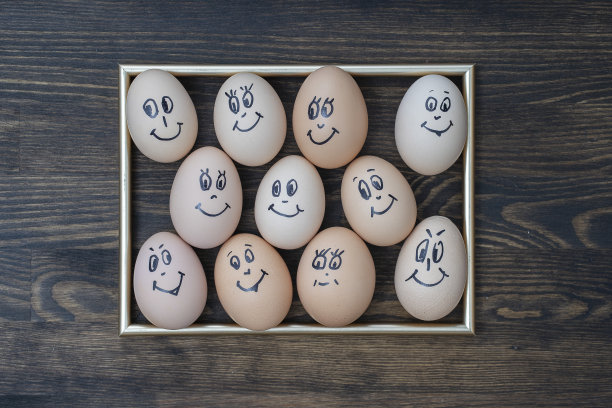图片的金色框架和许多有趣的鸡蛋微笑在黑暗的木墙背景。鸡蛋家庭情感面部肖像。概念有趣的食物图片下载