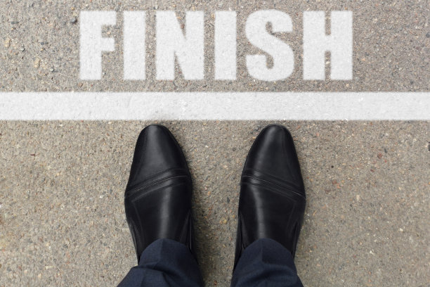 经营理念。顶视图的鞋子站在柏油路与线和字完成。黑色的鞋在柏油路纹理与完成白线图片下载